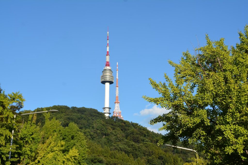 N Seoul Tower atop green Namsan hill against a clear blue sky, an iconic Seoul landmark