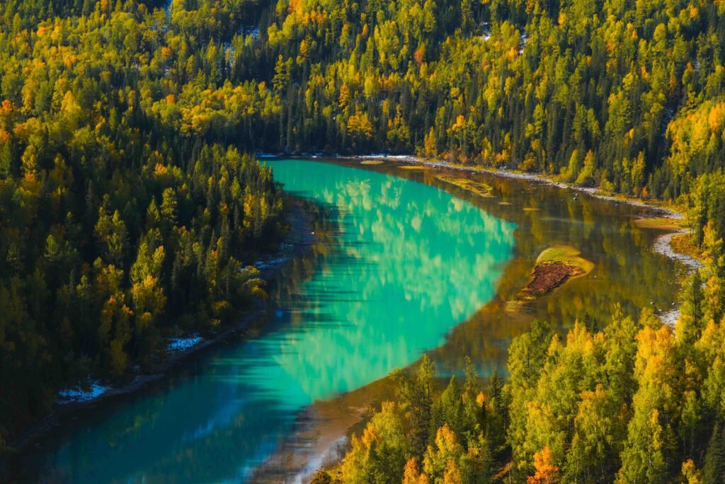 Best Time to Visit China: When Crowds Change the Entire Travel Experience Turquoise river winding through golden autumn forest at Kanas Lake, Xinjiang, China