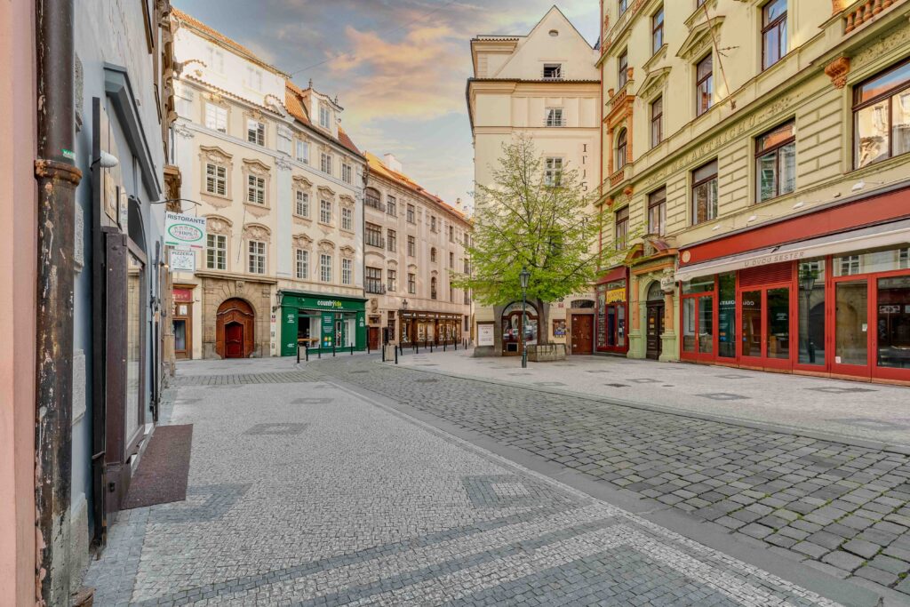 Quiet cobblestone square in Prague old town at sunrise with cafes and empty streets