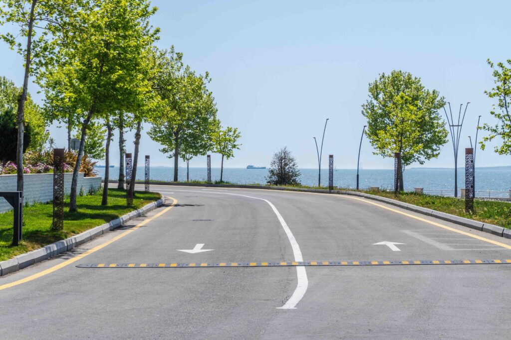 Empty seaside road with two arrows pointing opposite directions over a speed bump on a sunny day