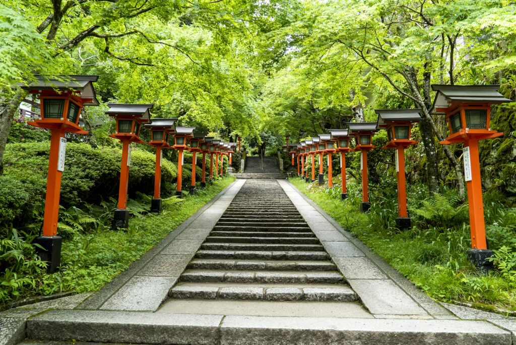 How Long to Stay in Japan: When the Pace Starts to Wear You Down Stone steps lined with red lanterns through green forest in Kyoto, how long to stay in Japan guide