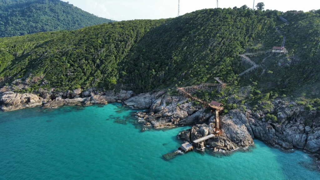 Off the Beaten Path in Malaysia: Hidden Gems and Underrated Destinations for a Peaceful Getaway Turquoise cove and forested hillside with a wooden jetty on a quiet Perhentian island, Malaysia