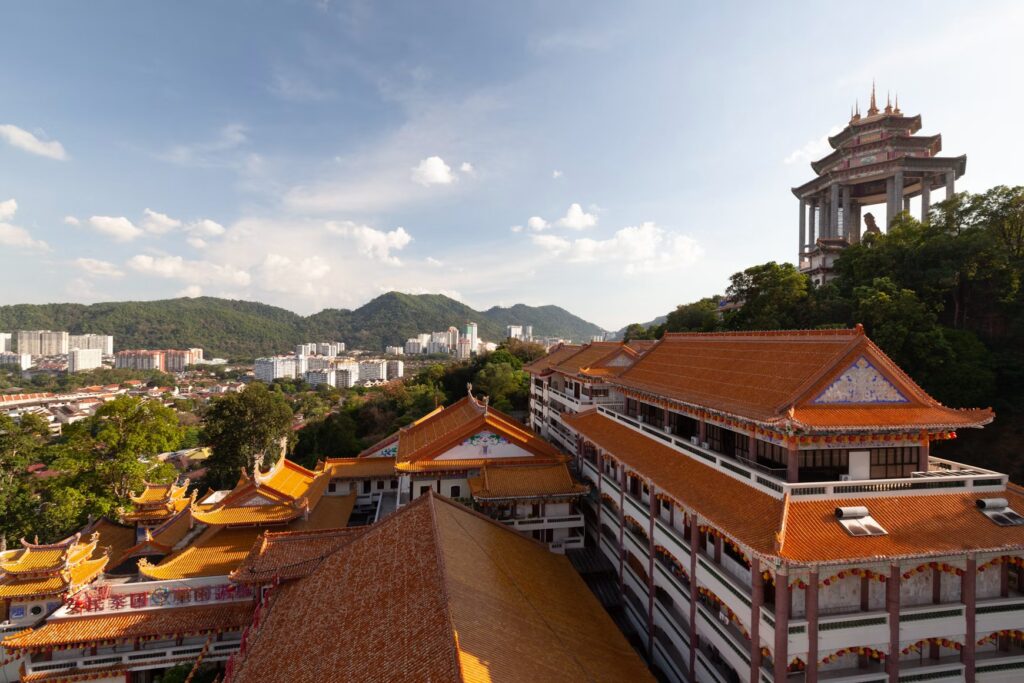 Penang Travel Guide: Food, Culture, and the Soul of Malaysia Tiered orange rooftops of Kek Lok Si Temple above Penang town under a blue sky, Malaysia.