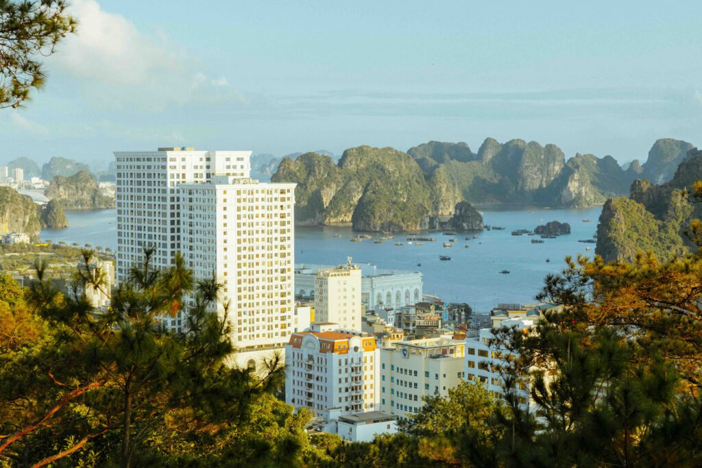 Southeast Asia and the Ease–Fatigue Curve of Remote Travel High-rise buildings beside Ha Long Bay with limestone karsts and boats in northern Vietnam