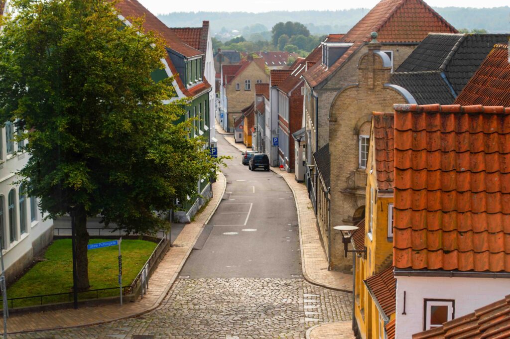 Quiet cobblestone street winding between old tiled-roof houses in a calm Danish town