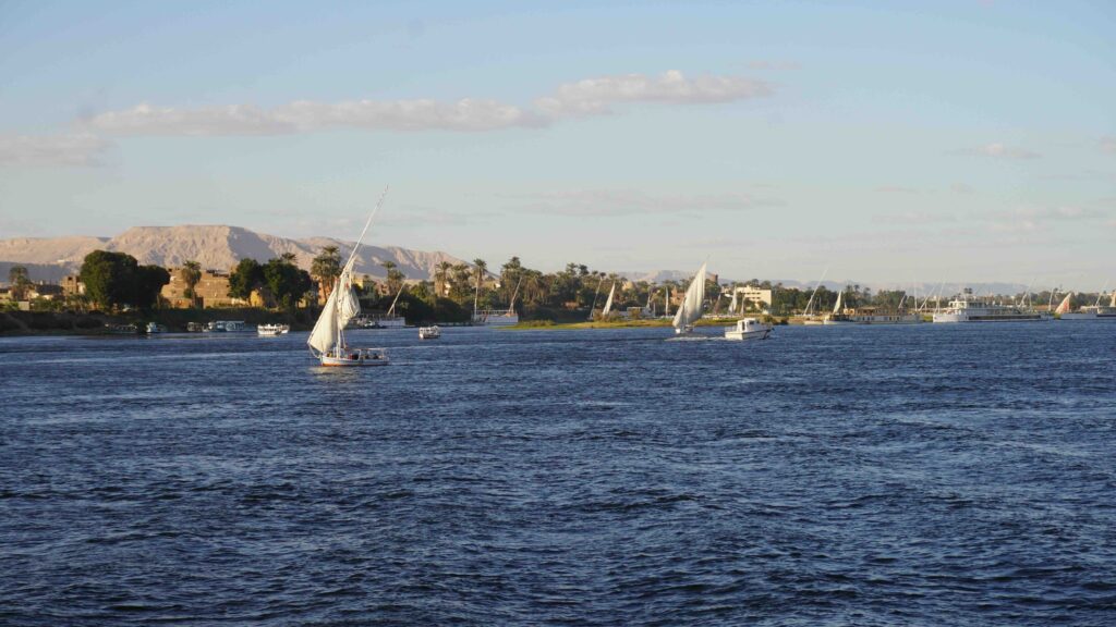 Ultimate Guide to Nile River Cruises: Top Tips, Attractions, and Expert Travel Advice for First-Time Visitors Traditional felucca sailboats cruising along the serene Nile River with mountains in the background.