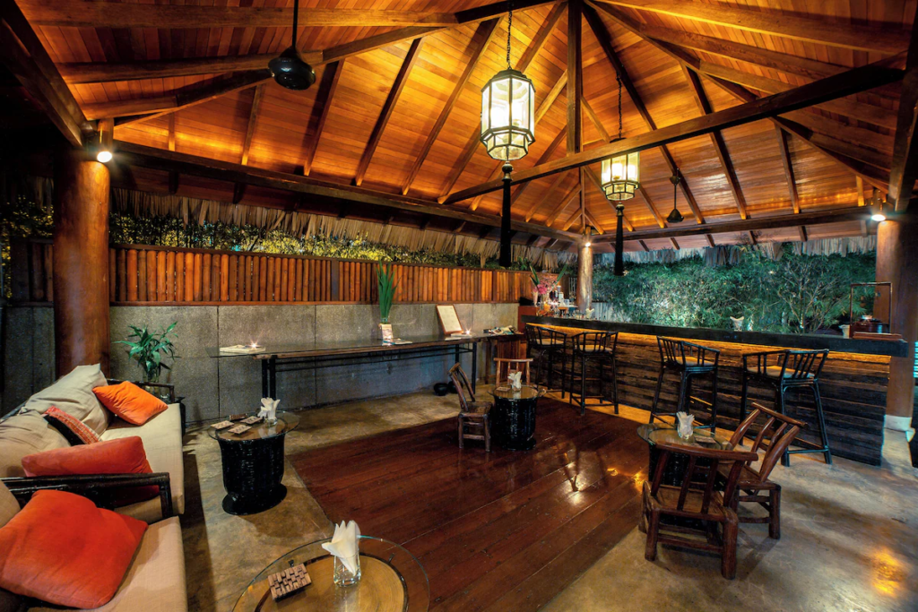 An atmospheric, open-air wooden dining pavilion with warm lanterns at Villa Samadhi Kuala Lumpur.