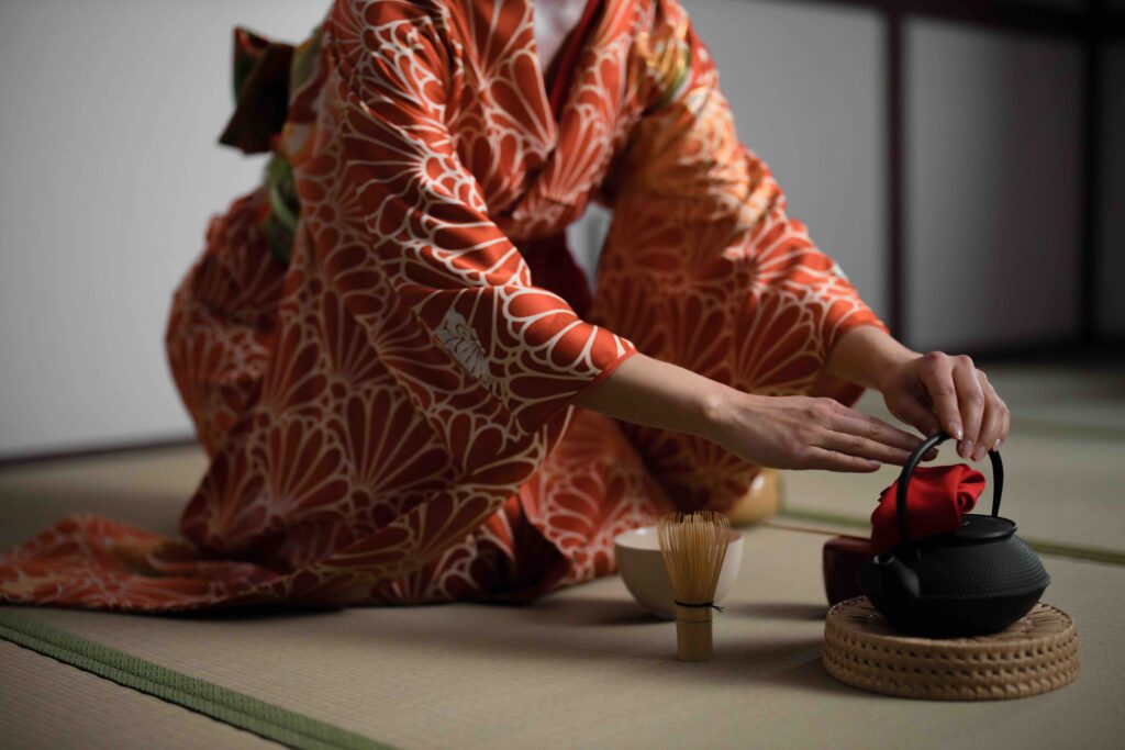 Essential Japanese Customs and Etiquette Tips Every Traveler Should Know Before Visiting Person in a kimono preparing tea on a tatami mat, essential Japanese customs and etiquette tips