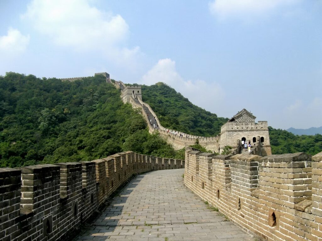 How to Avoid Common Travel Pitfalls in China: Essential Tips for First-Time Visitors Stone pathway of the Great Wall of China winding over green hills, travel tips for first-time visitors