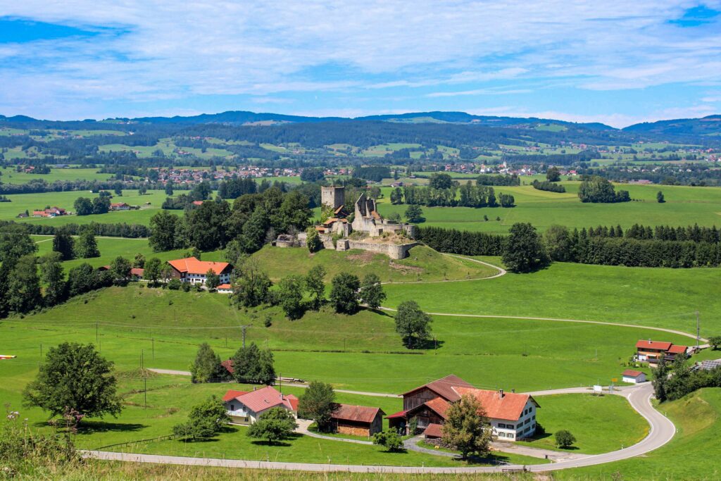 How to Plan a Road Trip Through Germany: Top Scenic Routes and Must-Visit Cities Winding road through green Bavarian countryside with a hilltop castle, a Germany road trip guide