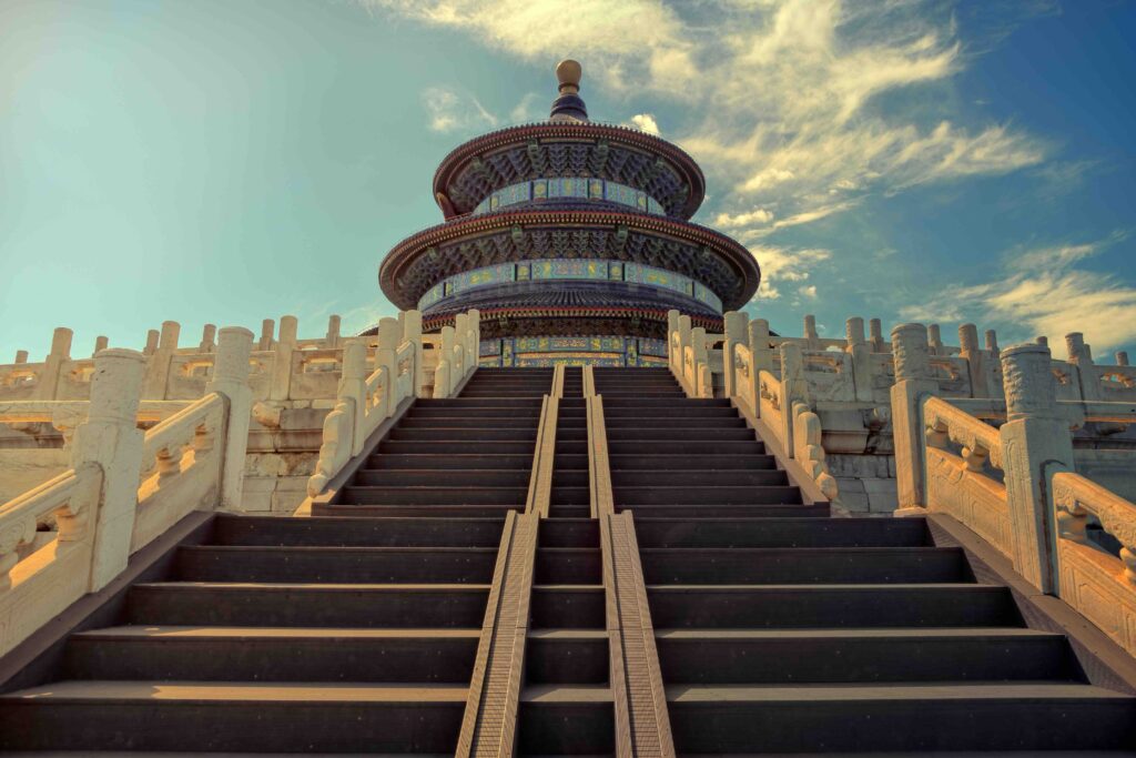 The iconic Temple of Heaven in Beijing, a circular building with blue tiered roofs, set on a white marble platform.