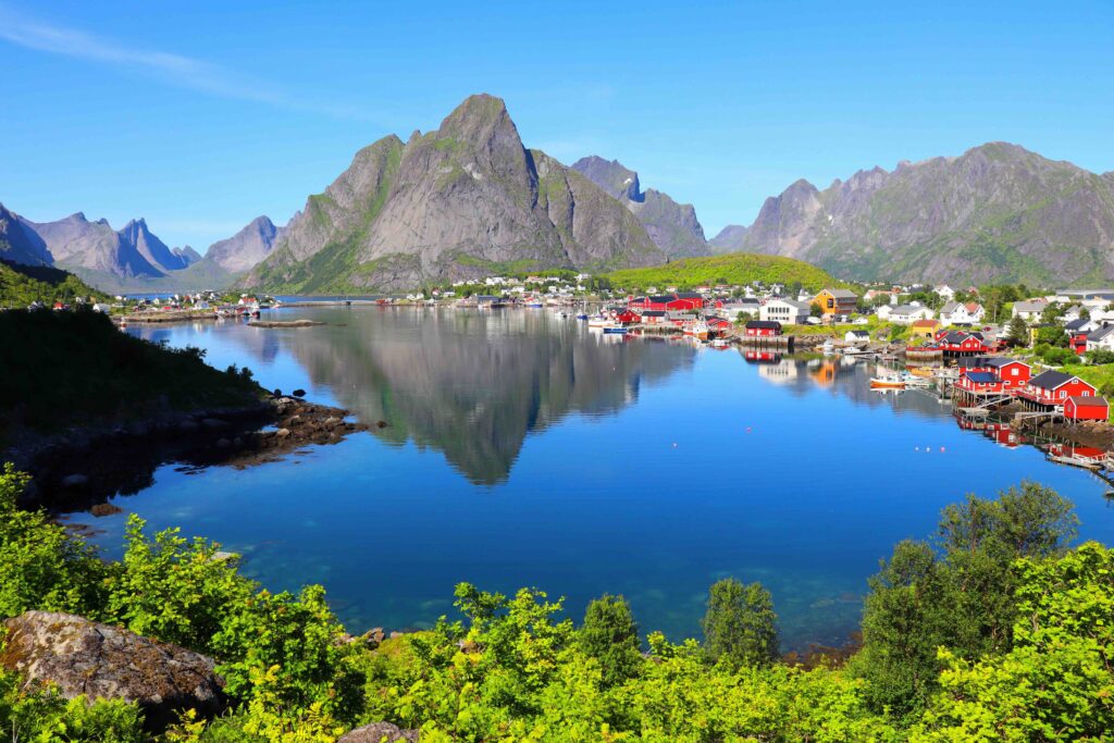 Best Places to Visit in Norway: Top Destinations, Must-See Sights, and Travel Tips Red rorbu cabins reflected in the turquoise fjord at Reine, Lofoten, Norway