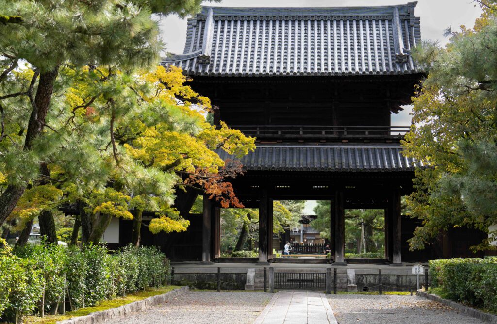 15 Best Places to Visit in September (2026): Crowd-Free Global Escapes A traditional wooden temple gate framed by autumn-colored trees in Kyoto, Japan.