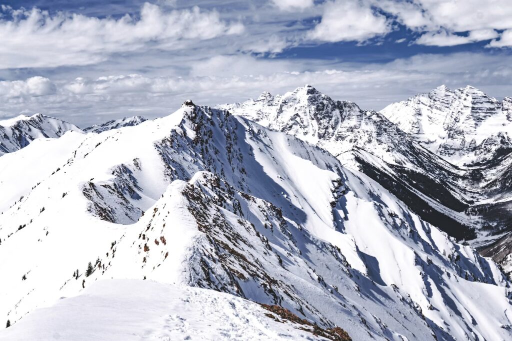 Dramatic snow-covered mountain ridges and peaks under a blue sky. 