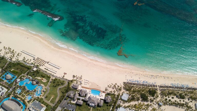 10 Best Caribbean Islands for Families (Where Parents Actually Relax in 2026) Aerial view of a stunning tropical beach and luxury pools, showcasing the best caribbean resorts for families