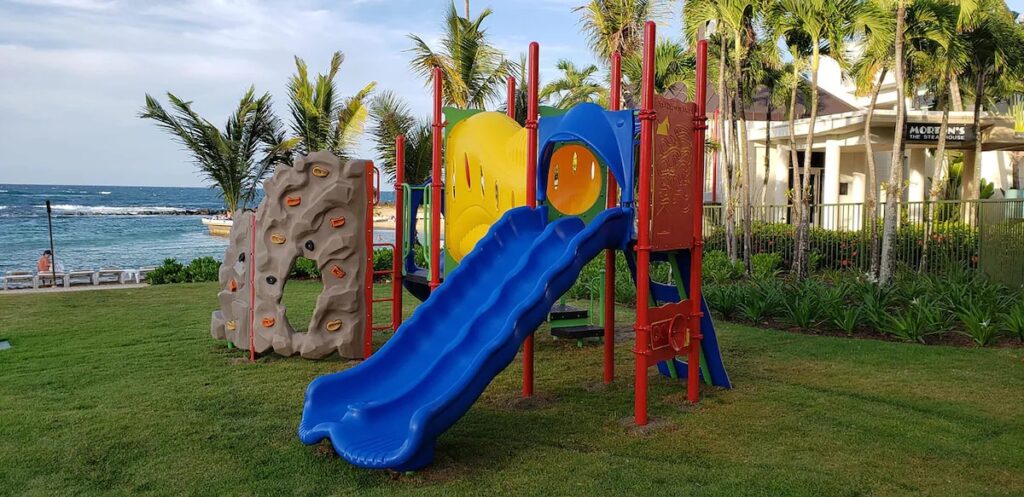 Colorful children's playground slide on a green lawn near the ocean 
