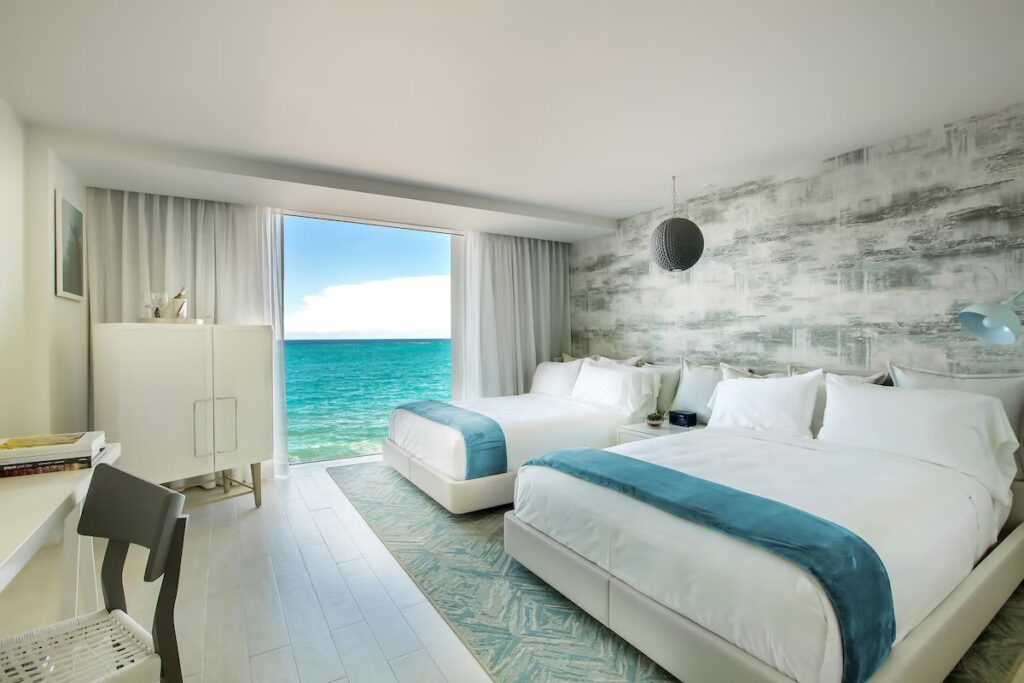 Bright modern double room with large windows facing the turquoise ocean 