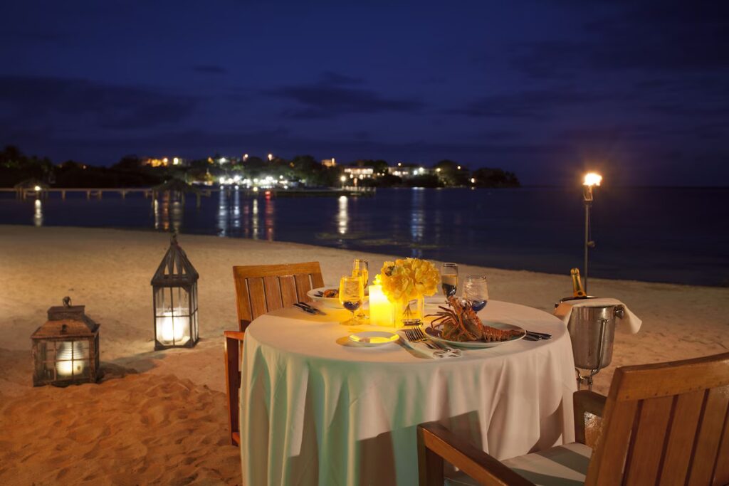 Romantic candlelit dinner setup on the beach at Copamarina Beach Resort at dusk 