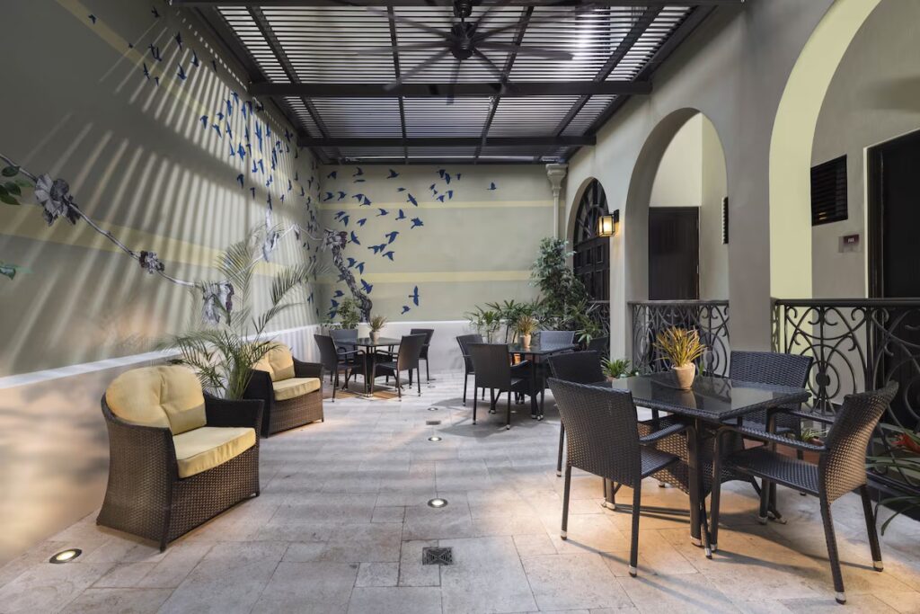 Open courtyard dining area with dark wicker seating at Decanter Hotel, one of the hotels in old san juan. 