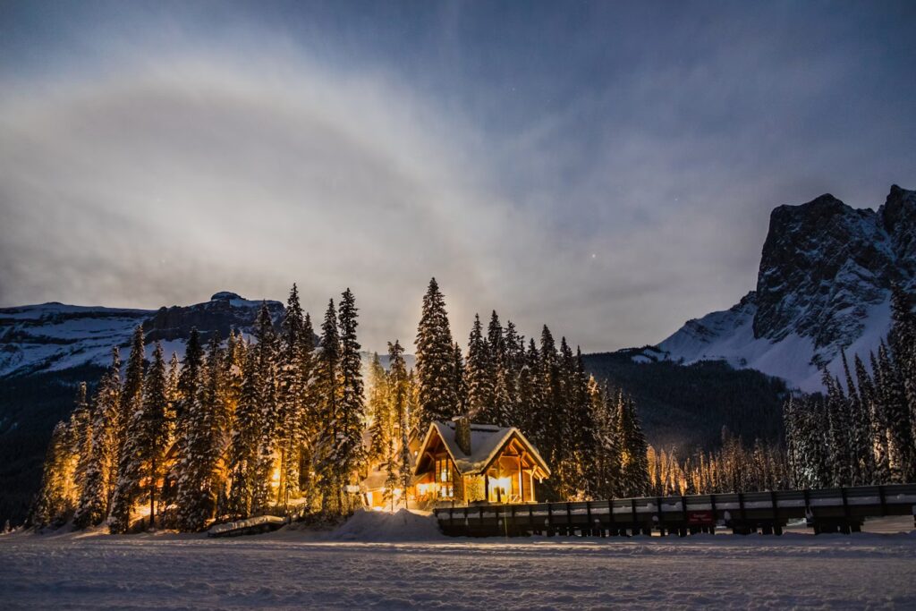 10 Best Places to Travel in December 2026: Underrated Countries A cozy mountain cabin glowing at night in a snowy landscape, one of the best places to travel in December.