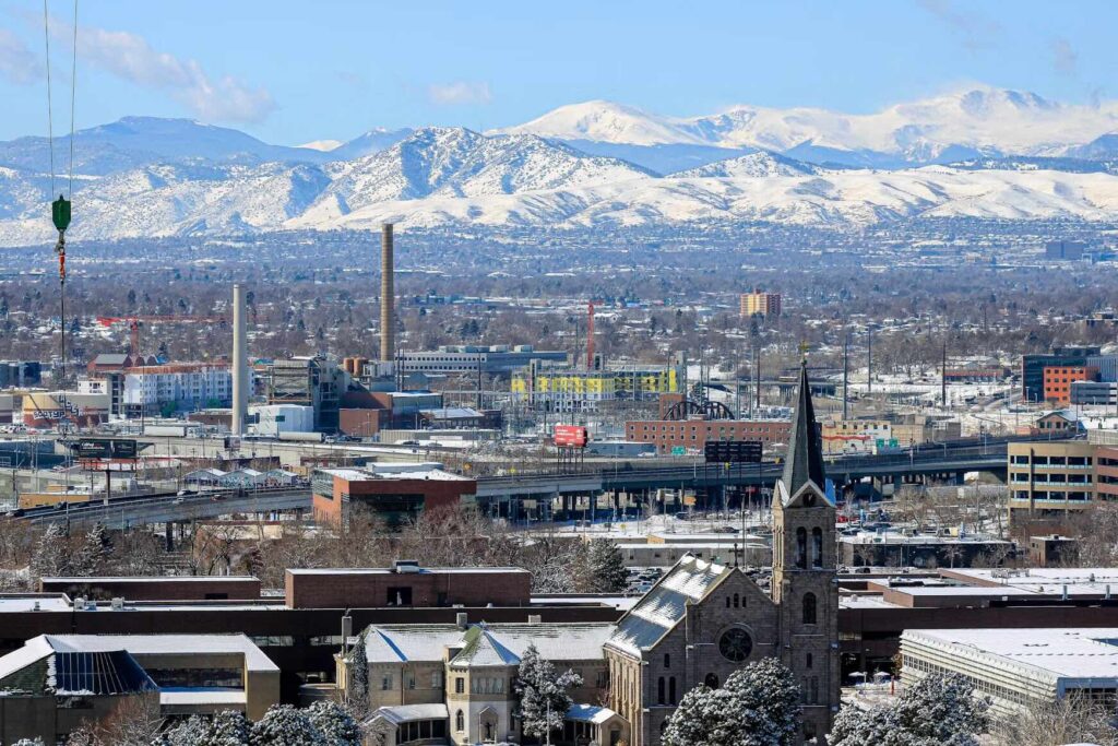 Denver city skyline with snow-capped mountains in the background. 