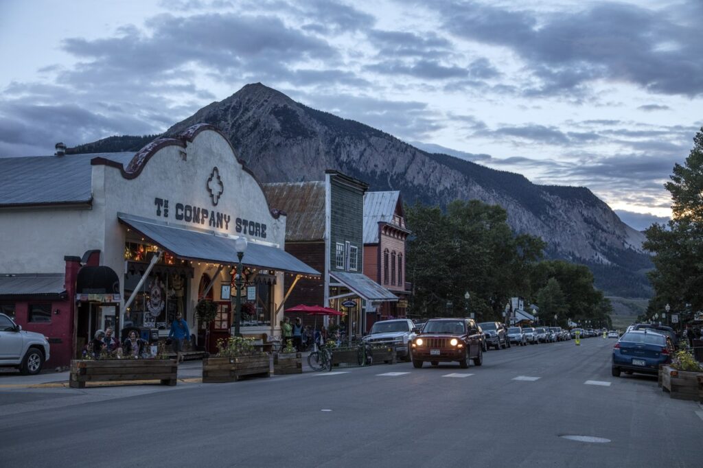 Cars parked along Elk Avenue in Crested Butte at twilight with a mountain backdrop. 