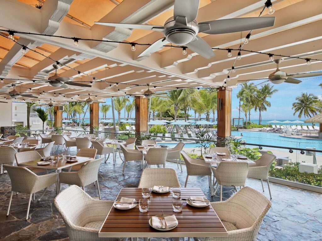 Covered outdoor dining patio with wicker chairs overlooking the beach 