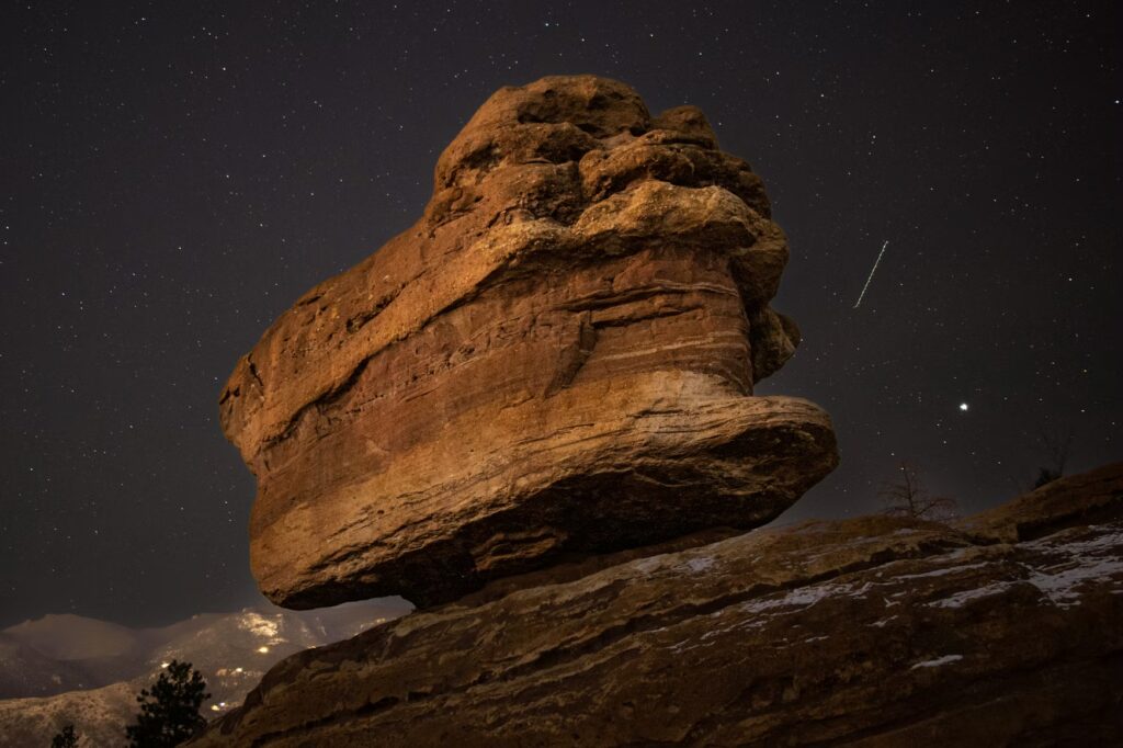 Balanced Rock formation illuminated at night under a starry sky. 