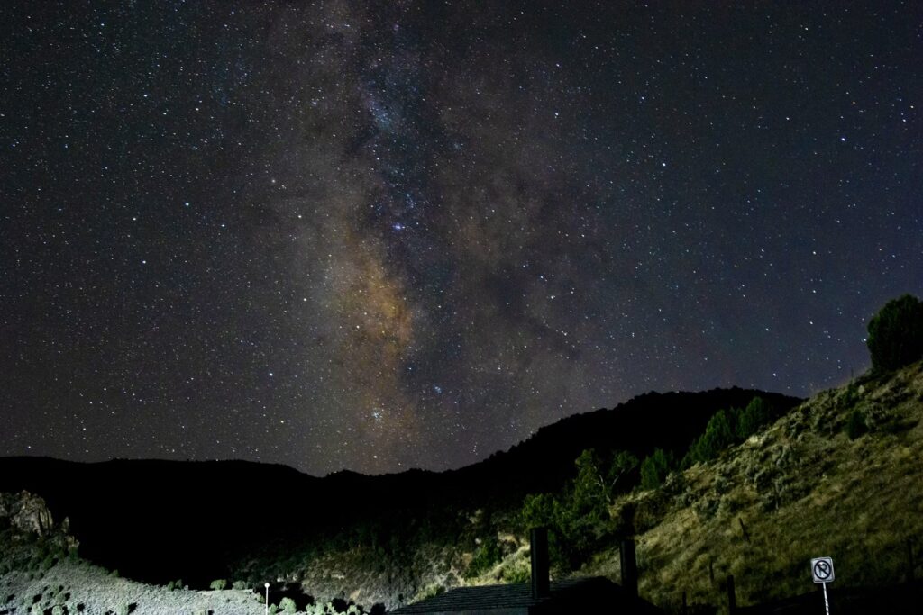 The Milky Way galaxy glowing brightly in the night sky above a dark mountain. 