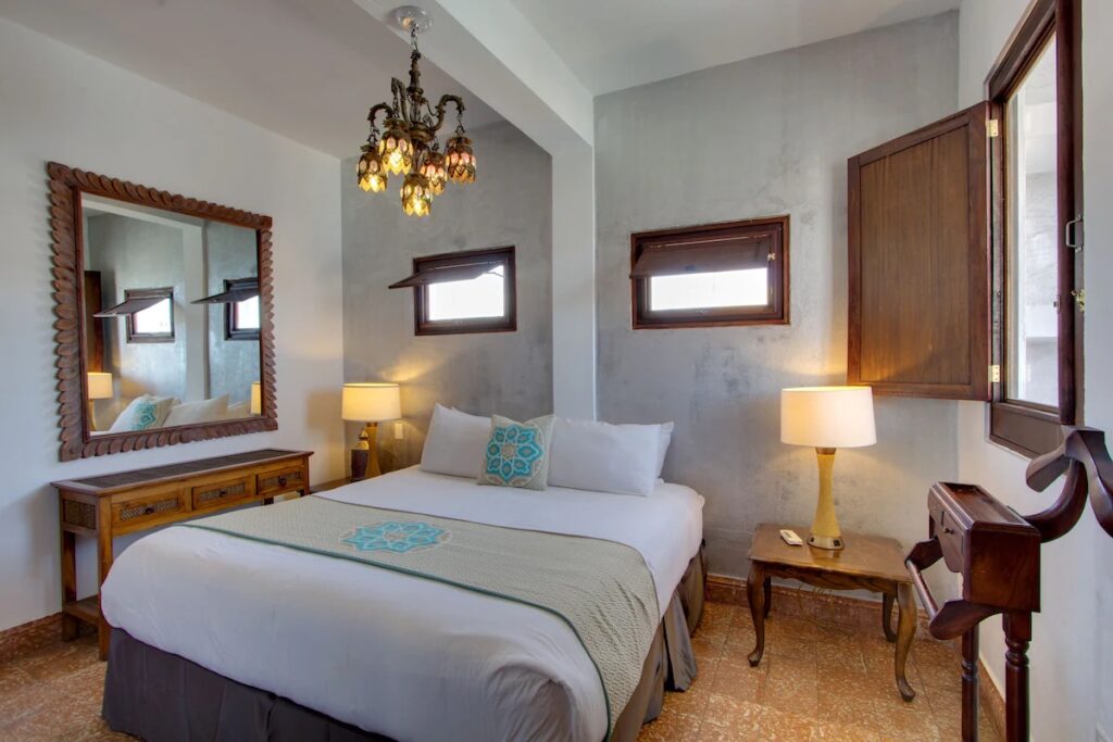 A classic, historic-style hotel bedroom featuring wooden furniture and a chandelier. 
