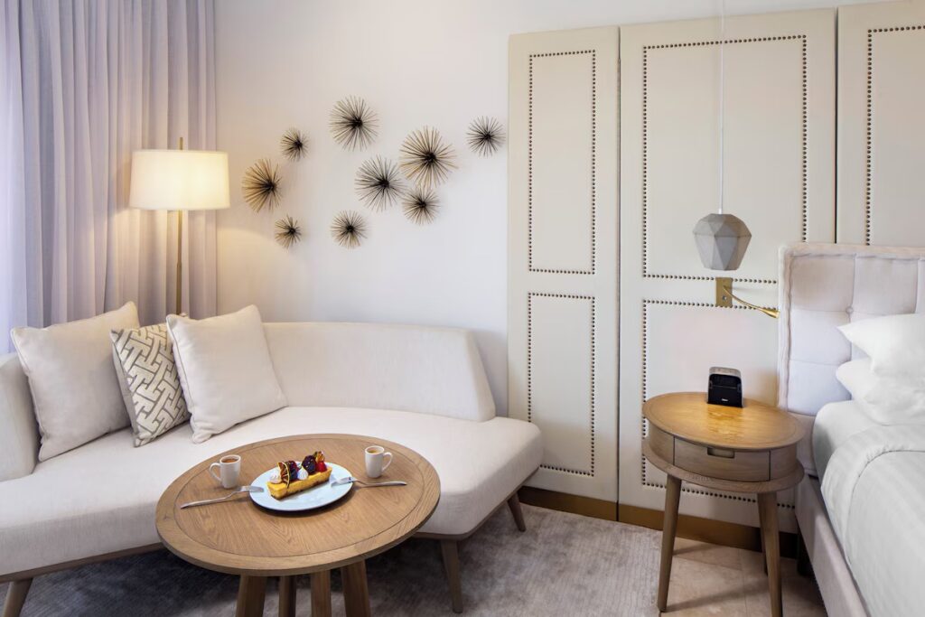 Elegant suite bedroom with a small dining table and a slice of cake 