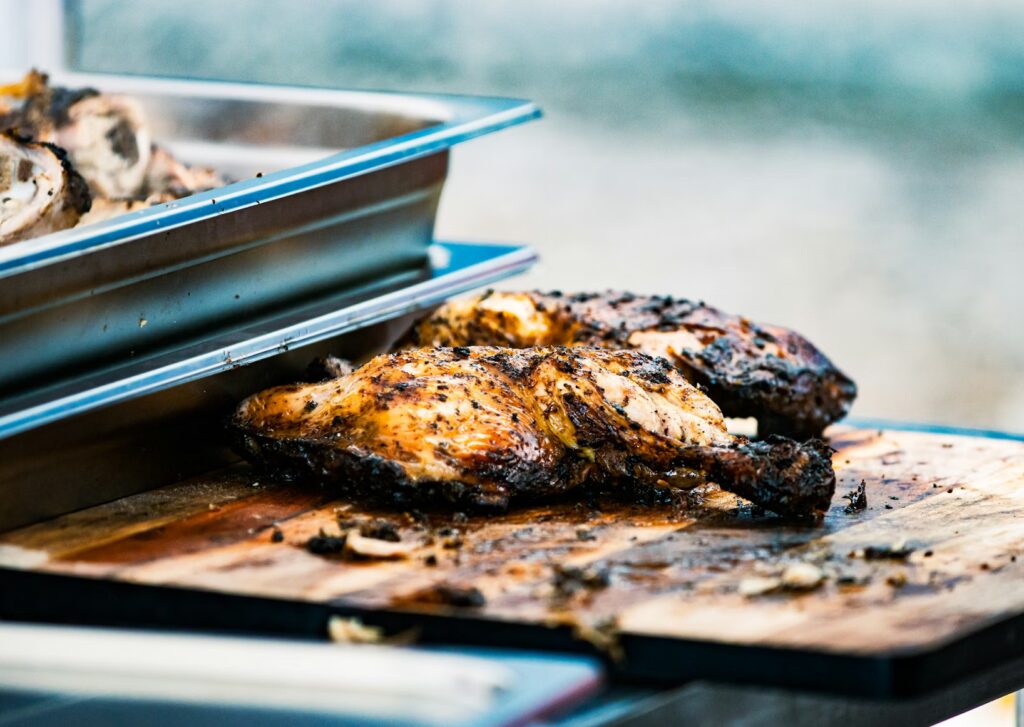 Authentic Jamaican jerk chicken on a wooden board, a delicious meal to try on a caribbean vacation with kids