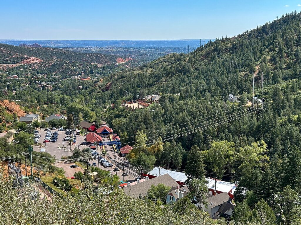 Looking down at the buildings of Manitou Springs nestled in a forested valley. 