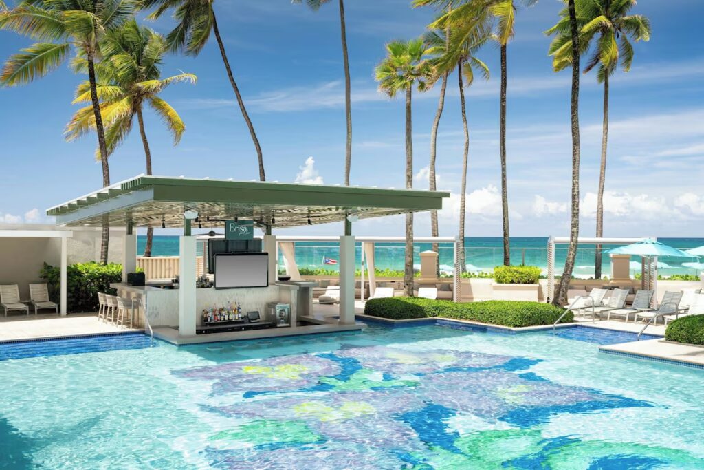 Swim-up pool bar with underwater stools and ocean views in the background 