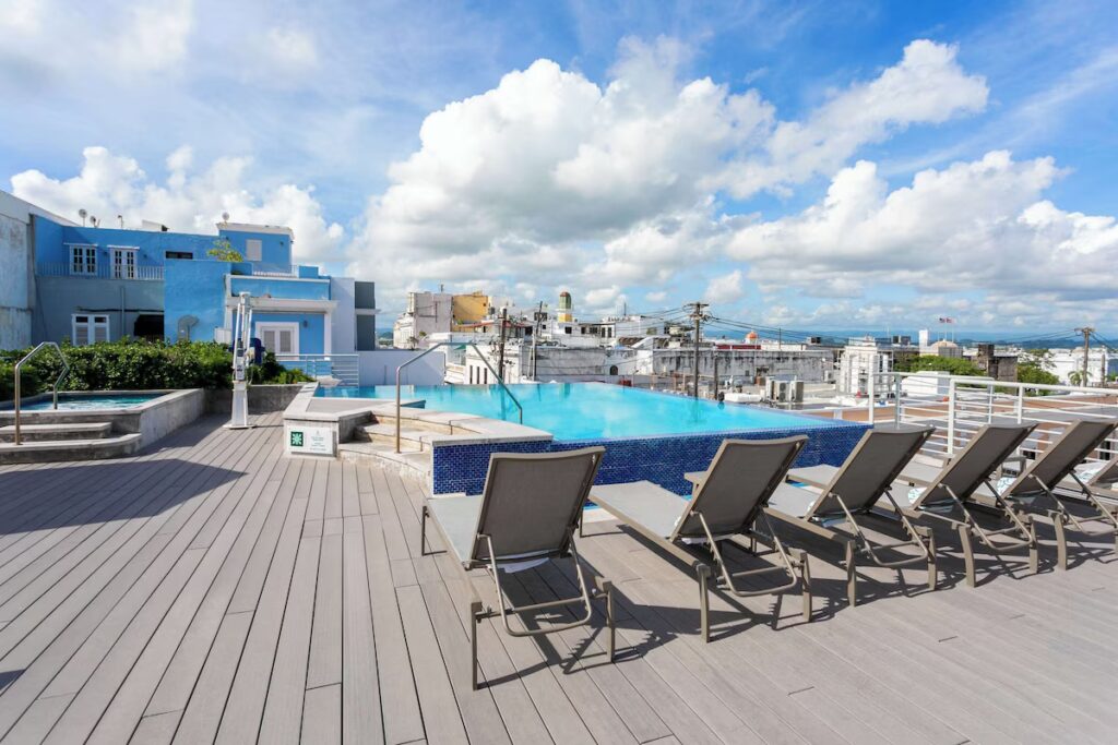 Rooftop pool and lounge chairs under a cloudy sky at Palacio Provincial. 