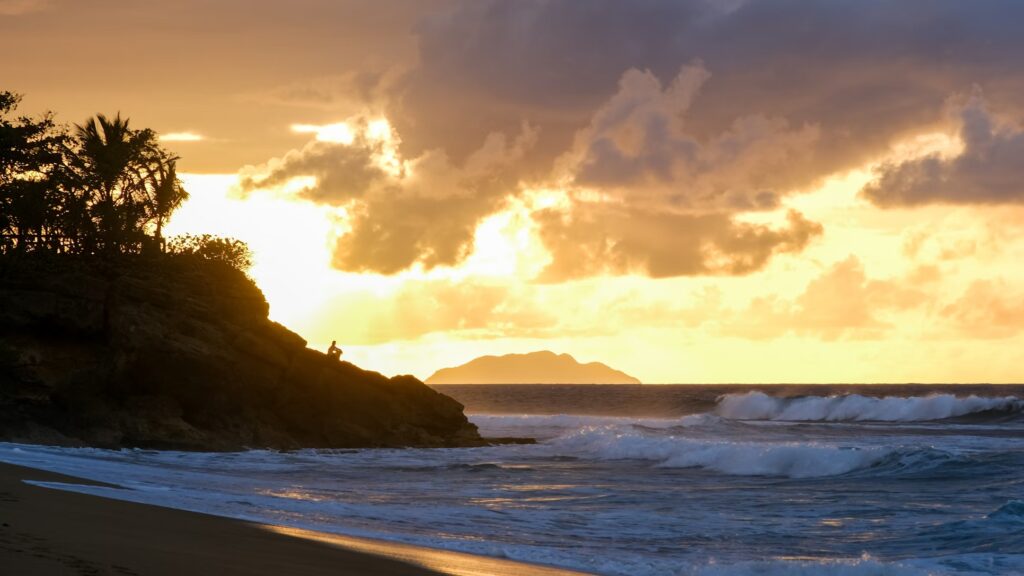 Sunset glow over a rocky point and beach in Rincón, a famous west coast surf town. 
