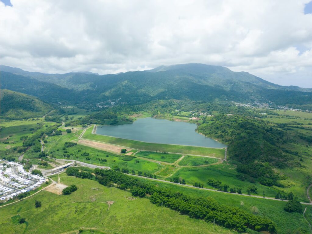 Aerial view of a serene lake surrounded by green mountains and valleys. 