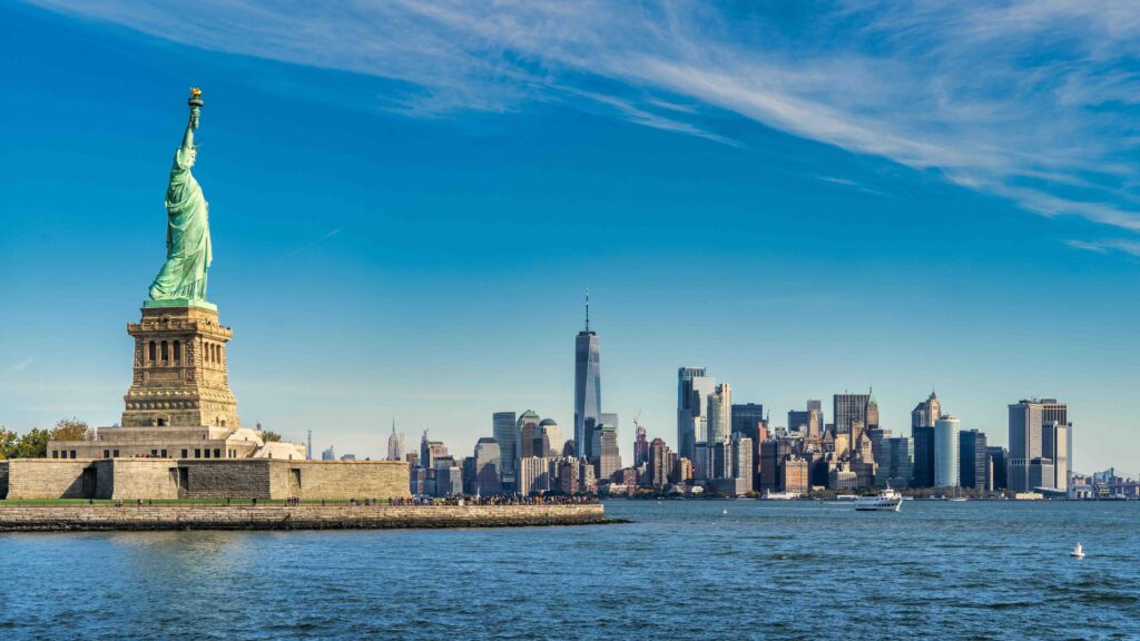 The Statue of Liberty standing proudly with the iconic New York City skyline as one of the top US travel destinations.