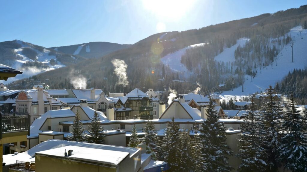 Steam rising from a snow-covered village at the base of a winter ski resort. 