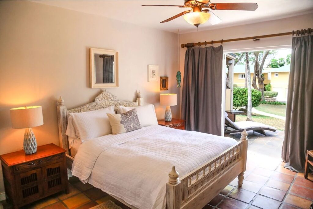 Cozy rustic bedroom with a carved wooden bed and open terrace door 