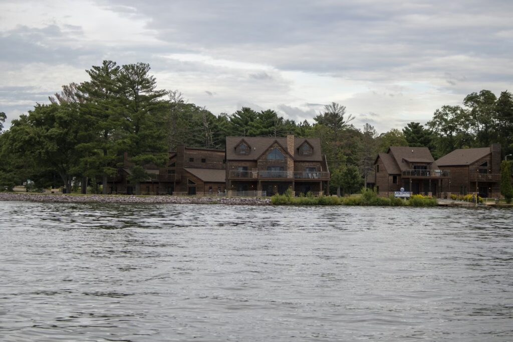 Lakeside wooden cabins surrounded by trees, viewed from across the water