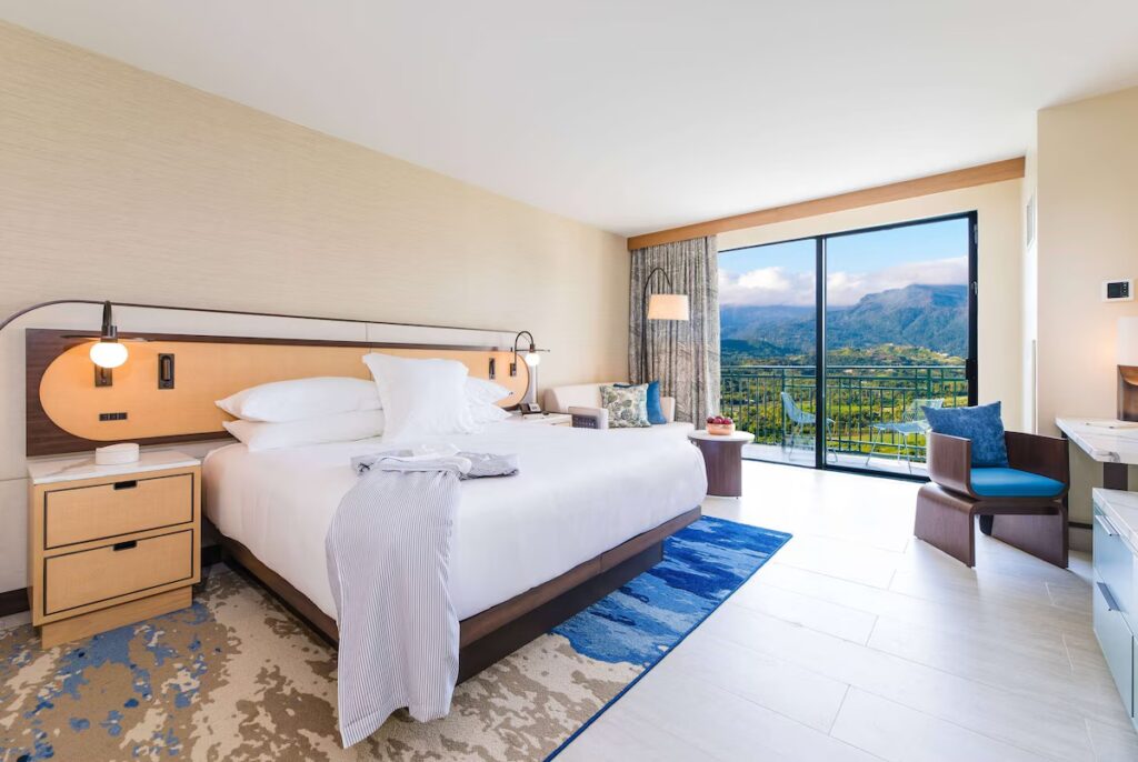 Bright hotel room with a king bed and balcony overlooking the mountains 