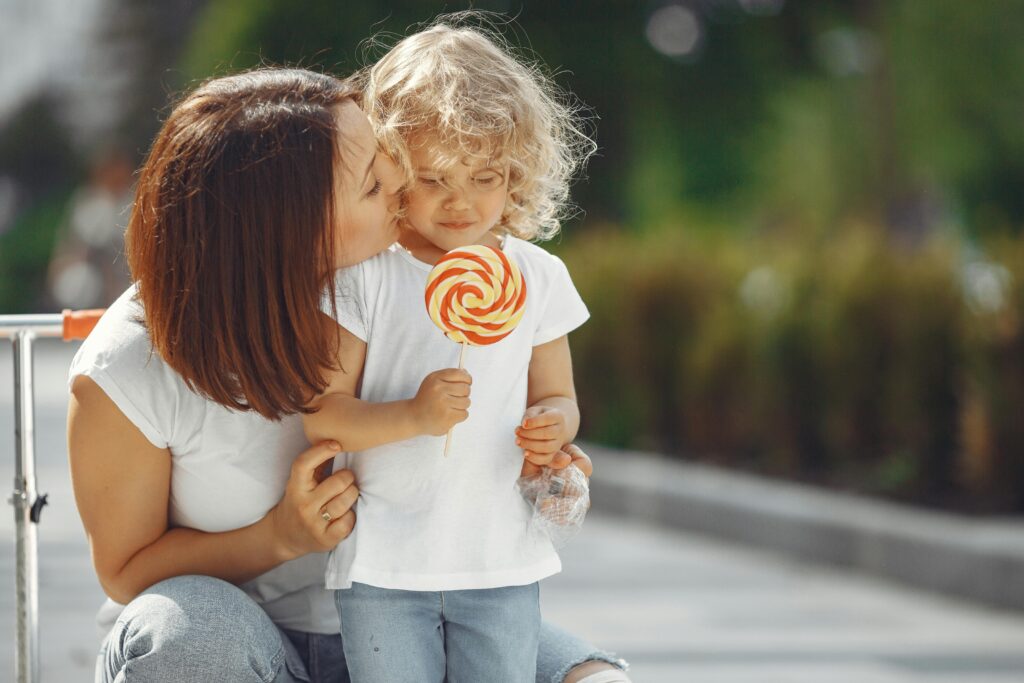 A mother comforting her pouting child with a lollipop, a genius family travel hack to manage hangry meltdowns during a trip