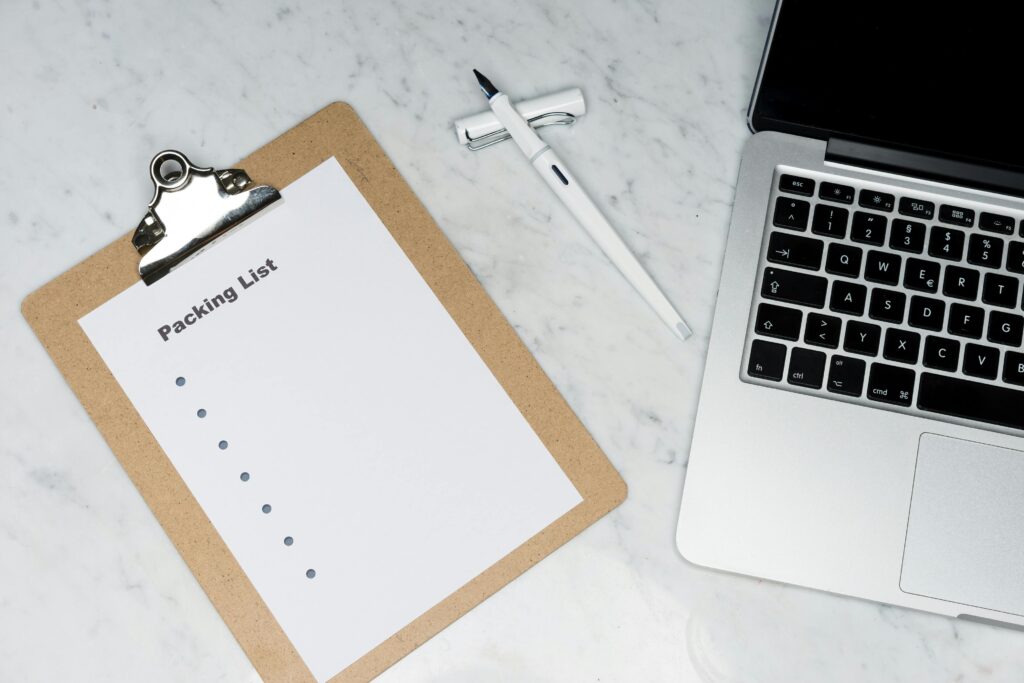 A blank packing list clipboard and laptop, essential for planning the best family vacations in the us