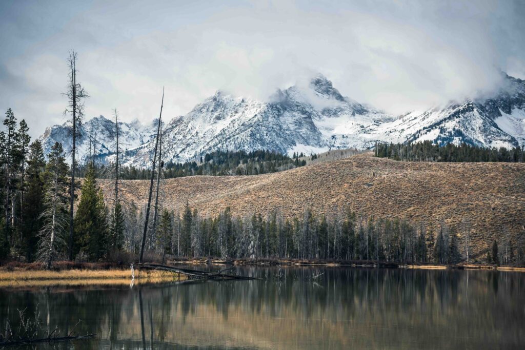 Calm lake reflecting snow-capped mountains in Stanley, Idaho, one of the top best family vacation spots