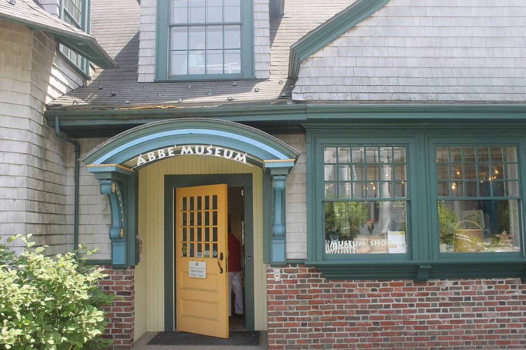 The historic entrance to the Abbe Museum in Bar Harbor featuring a yellow door and blue trim.
