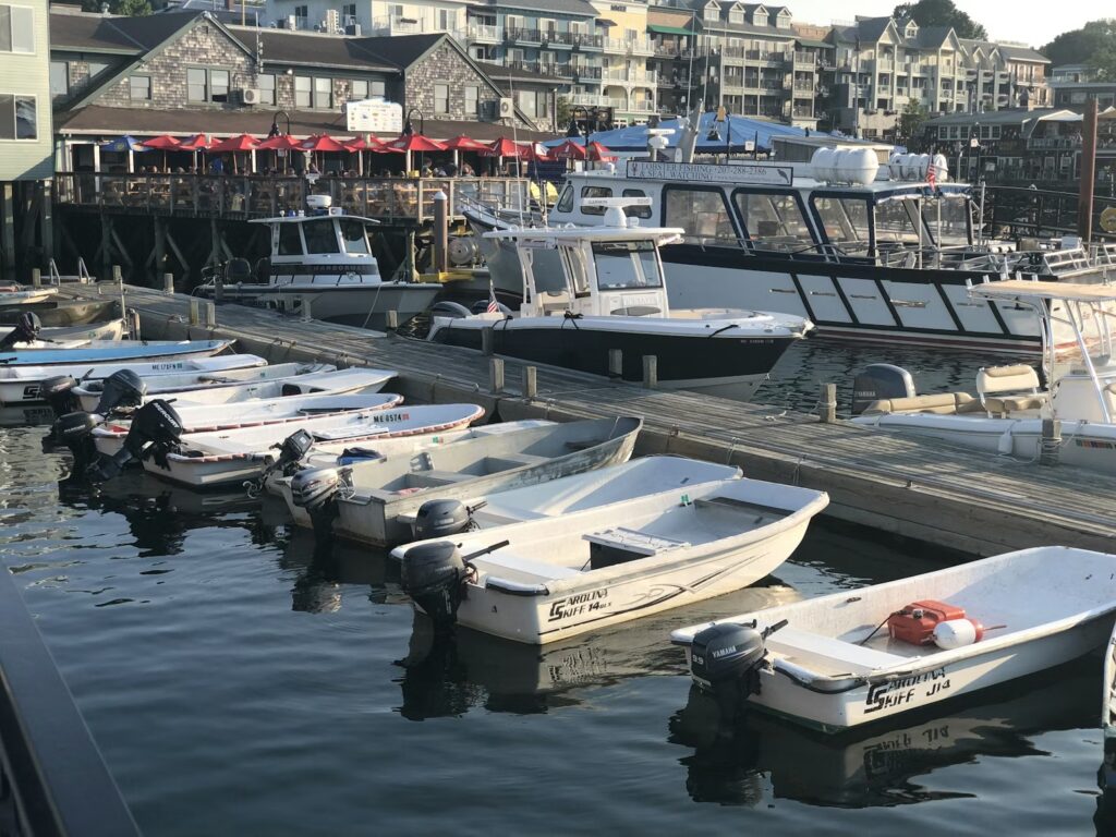 Small white motorboats docked closely together at a busy marina in Bar Harbor. 