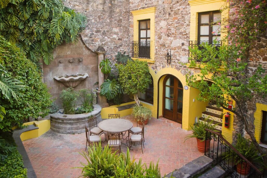 A historic colonial courtyard with a stone fountain and yellow stucco walls at Casa de Sierra Nevada.