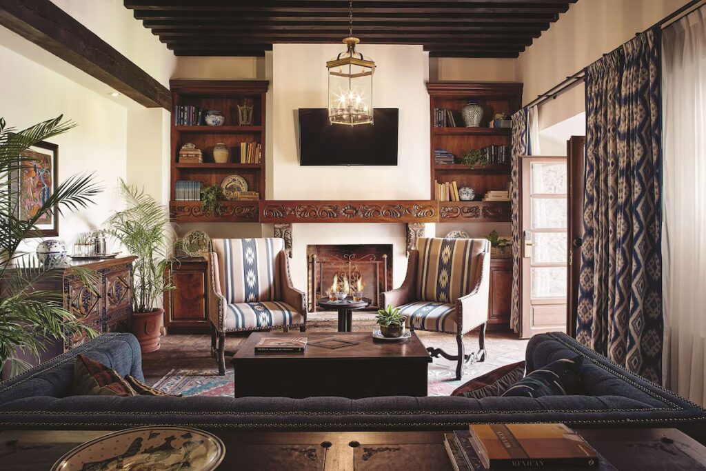 A cozy, traditional living room with a fireplace and exposed wooden ceiling beams at Casa de Sierra Nevada.