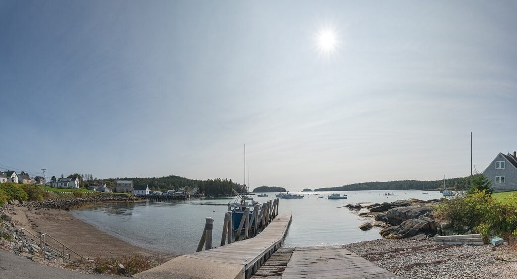 A working fishing harbor with moored boats and a boat ramp on a sunny day in Cutler, Maine.